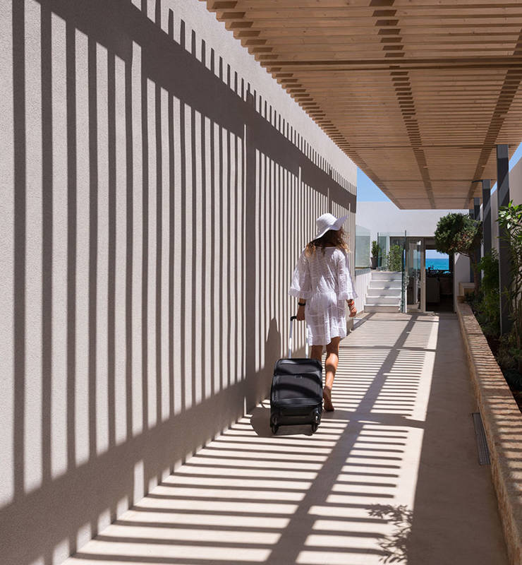 Cactus Bay visitor in white outfit with their suitcase walking in the hotel premises